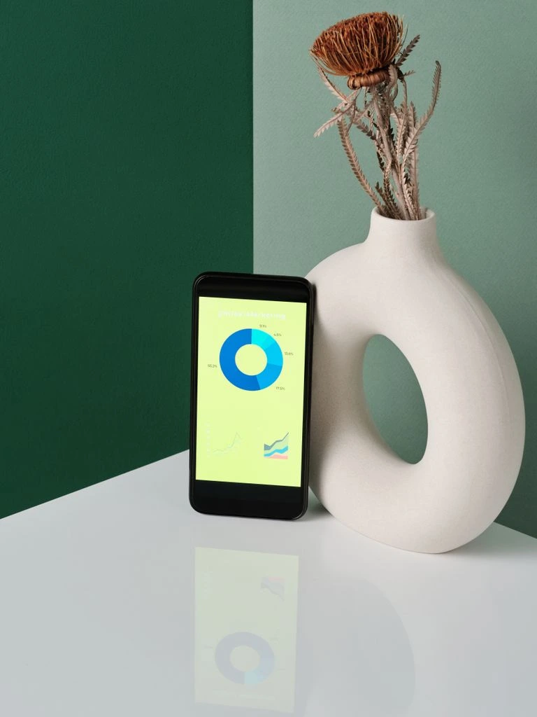 A phone propped against a ceramic vase, showing an audio waveform.